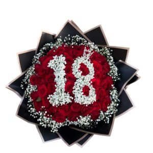 Top-down view of a bouquet of red roses, white baby's breath, and dark wrapping paper on a white background.